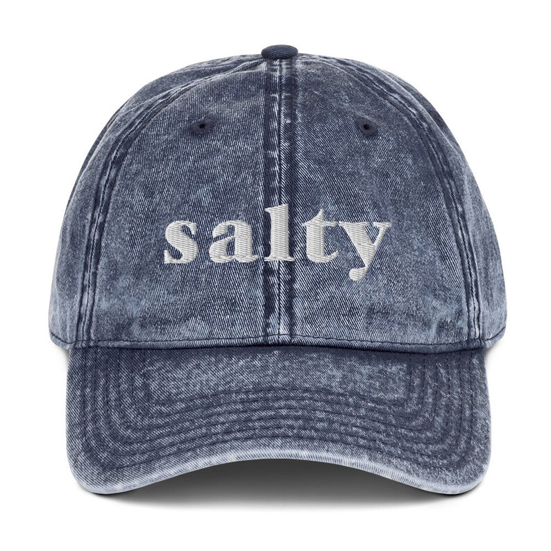 May include: A blue denim baseball cap with the word "salty" embroidered in white on the front.