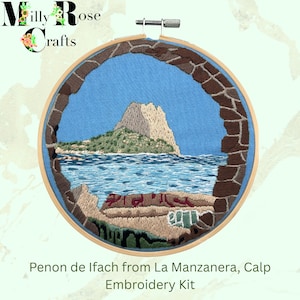 May include: An embroidery kit featuring a detailed landscape scene of Penon de Ifach from La Manzanera, Calp. The design is framed within a wooden hoop, showcasing a mountain, sea, and sky in shades of blue, green, and brown. The text "Embroidery Kit" is visible.