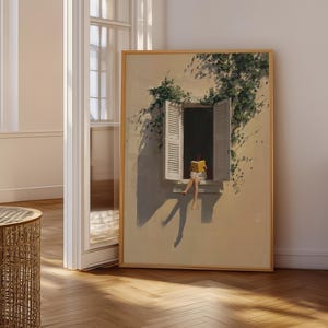 May include: A framed art print depicts a person reading a book while sitting in a window. The artwork features a warm color palette with a beige background, a window with open shutters, and green vines. The person is wearing a yellow dress.
