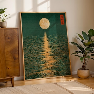 May include: A framed rectangular wall art print featuring a full moon over dark green water with golden ripples. The artwork includes a vertical red rectangular element with Japanese text in the upper right corner, set in a light wooden frame.