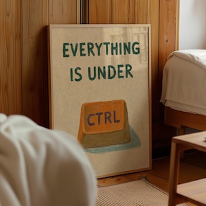 May include: A framed rectangular wall art print featuring a beige background with the dark green text "EVERYTHING IS UNDER" positioned above an illustration of an orange computer keyboard key with the blue text "CTRL" printed on its surface.