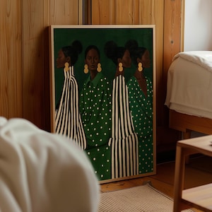 May include: A framed rectangular wall art print featuring four figures with dark skin and hair in buns, wearing green and white patterned clothing. The figures are dressed in alternating striped and polka dot garments, accented with gold circular earrings.