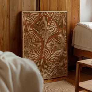 May include: A rectangular framed wall art piece featuring a repeating pattern of stylized ginkgo leaves in shades of muted olive green and cream against a solid terracotta orange background, enclosed within a light-toned wooden frame.