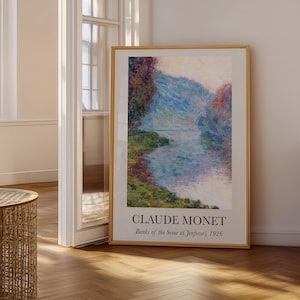 May include: A framed art print featuring Claude Monet's painting Banks of the Seine at Jeufosse, 1926. The artwork displays a river landscape with blue, green, and pink tones. The text CLAUDE MONET and Banks of the Seine at Jeufosse 1926 is printed below.