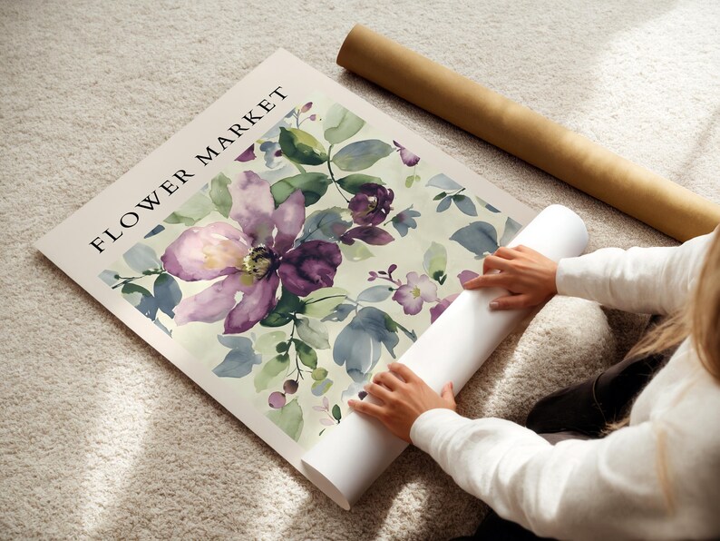 A person is placing a large poster with a floral design on a carpeted floor.