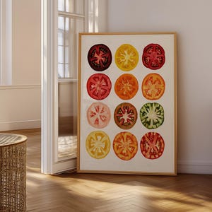 May include: A framed wall art print featuring a grid of twelve tomato slices in various colors including deep purple, yellow, bright red, orange, pale pink, brown, and green, all displayed against a plain white background within a light wood frame.