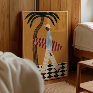 Puede incluir: Una lámina de arte enmarcada que muestra a una persona con sombrero blanco, camisa de rayas azules y blancas y pantalones claros, cargando una tabla de surf roja y blanca. La escena incluye una palmera, un fondo amarillo y un suelo de damero.