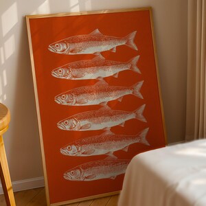 Könnte beinhalten: Gerahmter Kunstdruck mit sechs weißen Fischillustrationen auf leuchtend orangefarbenem Hintergrund. Das Kunstwerk befindet sich in einem Holzrahmen. Der Druck lehnt an einer Wand. Geeignet für Küche oder Esszimmer.