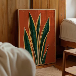 Peut inclure: Une impression d'art murale encadrée rectangulaire présentant une illustration stylisée d'une plante serpent avec de longues feuilles pointues vert foncé bordées de jaune, sur un fond orange brûlé uni dans un cadre en bois clair.