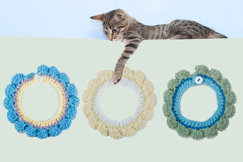 May include: Three crocheted cat collars in blue, yellow, and green with a button closure. The collars have a ruffled edge and are made with a variety of stitches.
