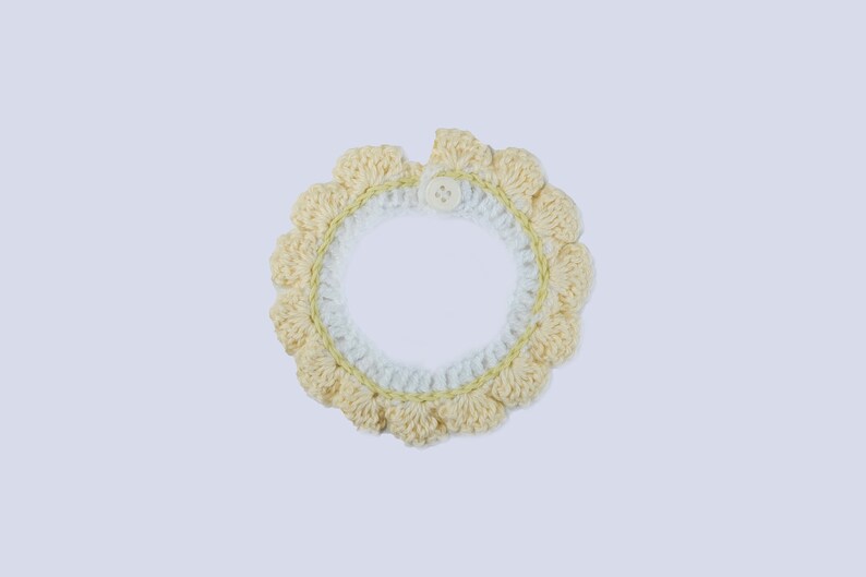 May include: A crocheted collar with a white and yellow design and a single button closure.