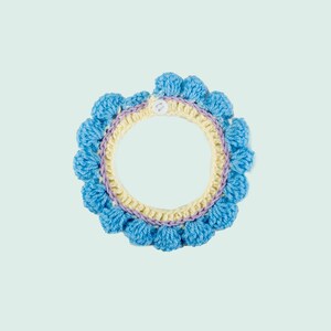 May include: A crocheted collar with a light blue, yellow, and purple design. The collar has a button closure.