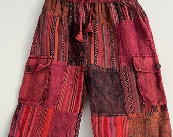 Pode incluir: Shorts de patchwork vermelho, marrom e preto com cintura de cordão e dois bolsos grandes nas laterais. Os shorts têm um padrão geométrico.