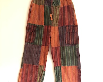 May include: Patchwork trousers with a drawstring waist and two side pockets. The trousers are made of a variety of colourful striped fabrics in shades of orange, green, purple, and brown.