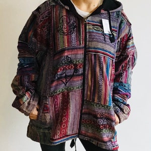 May include: A multi-coloured patchwork hooded jacket with a zip closure. The jacket features a variety of patterns and designs, including stripes, geometric shapes, and floral motifs. The hood is lined with black fabric.