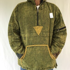 May include: A green hooded sweatshirt with a yellow triangle patch on the front and a zip closure. The sweatshirt has a large pocket on the front and a zipped pocket on the sleeve.
