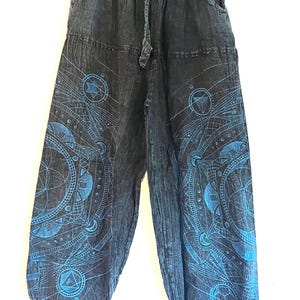 May include: Dark blue harem pants with a drawstring waist and pockets. The pants feature a geometric design in shades of blue. The design includes circles, triangles, and other geometric shapes. The pants are made of a soft, flowing fabric.