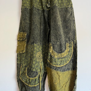 May include: Green and black patterned pants with a drawstring waist and multiple pockets. The pants have a geometric design and are made of a soft, comfortable fabric.