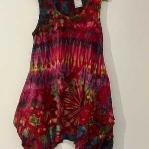 May include: A sleeveless tie-dye dress in a red, pink, blue, green and yellow colour scheme. The dress has a scoop neck and a loose, flowing fit.