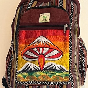 May include: A burgundy backpack with a colorful embroidered mushroom design. The backpack features a front pocket with a zipper, adjustable straps, and a tag that reads "Himalayan Hemp THC Free". The bag has a patterned design with various colors.