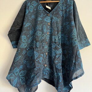 May include: A black and blue patterned button-up shirt with a V-neck and a slightly asymmetrical hem. The shirt is made of a lightweight fabric and has a relaxed fit.