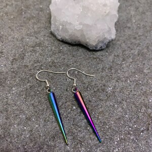May include: A pair of iridescent silver earrings with a pointed, teardrop-shaped design.