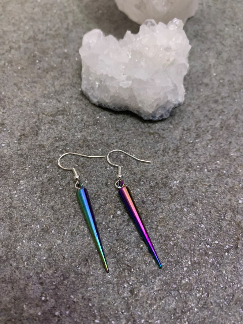 May include: A pair of iridescent silver earrings with a pointed, teardrop-shaped design.