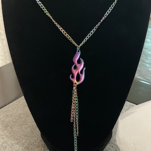 May include: A silver chain necklace with a rainbow iridescent flame pendant and a dangling chain tassel.