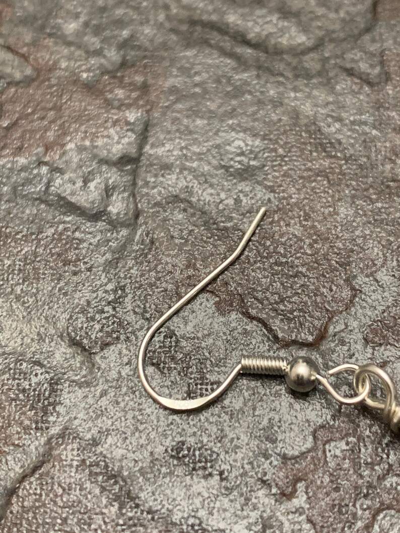 May include: Silver earring hook with a small ball at the end. The hook is made of metal and has a smooth finish.