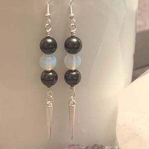 May include: Silver dangle earrings with black and white round beads and silver spikes.