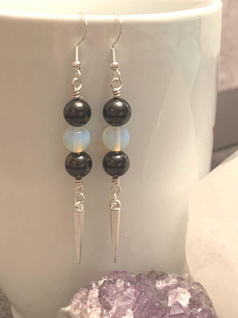May include: Silver dangle earrings with black and white round beads and silver spikes.