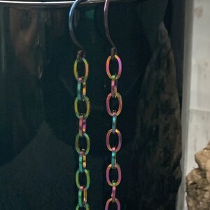 May include: A pair of iridescent chain earrings with a hook closure. The chain is made of small, oval-shaped links.