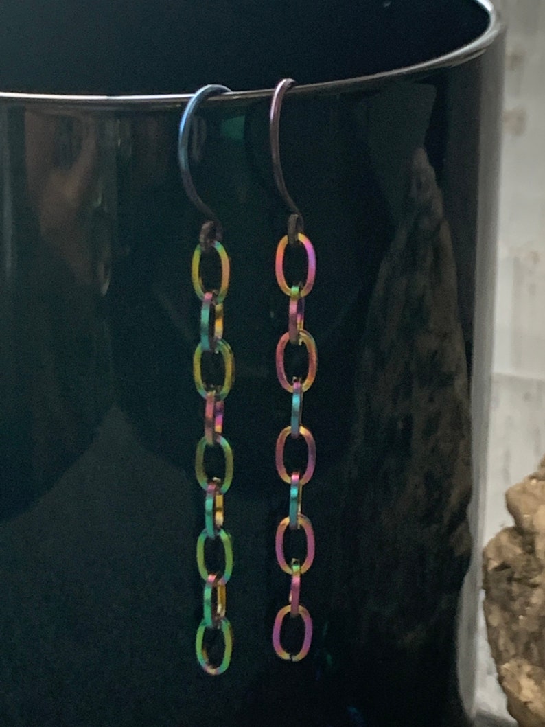 May include: A pair of iridescent chain earrings with a hook closure. The chain is made of small, oval-shaped links.