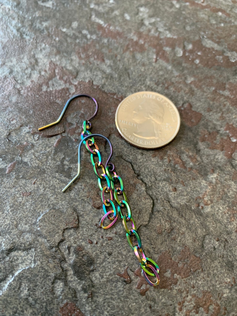 May include: A single iridescent chain earring with a hook closure. The earring is shown next to a US quarter for size comparison.