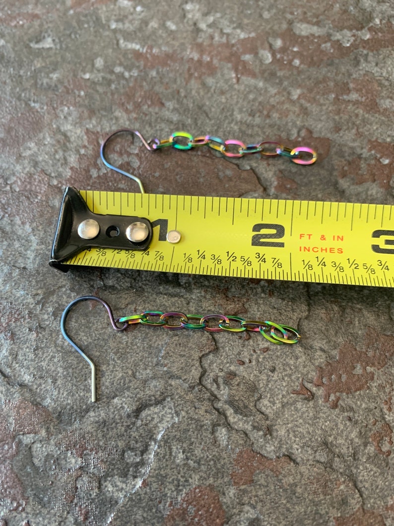 May include: Two rainbow-colored chain earrings with a hook closure. The earrings are measured against a yellow tape measure, showing they are approximately 1 1/2 inches long.