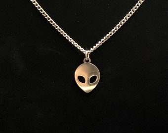 May include: A silver chain necklace with a silver alien head pendant.