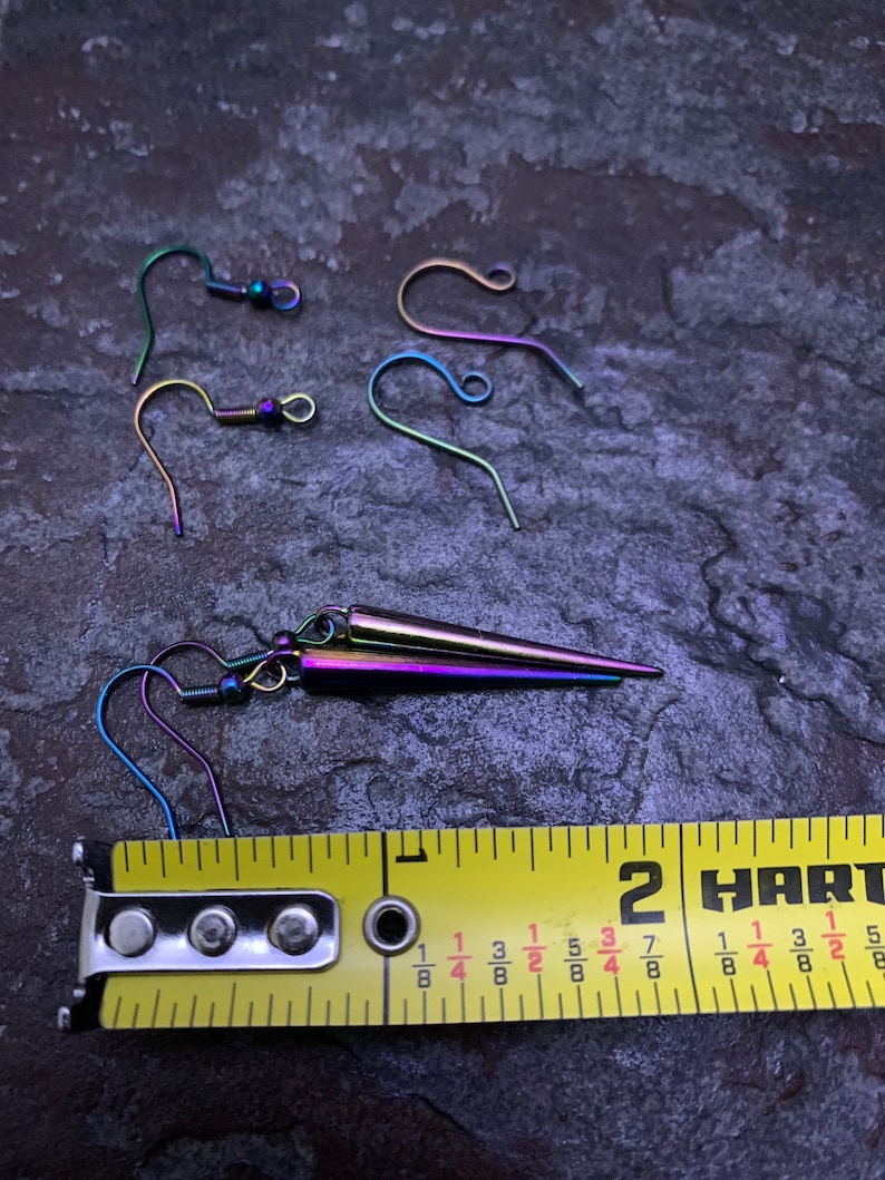 May include: A pair of rainbow iridescent earrings with a pointed design. The earrings are approximately 1 3/8 inches long. The earrings are shown next to a measuring tape.
