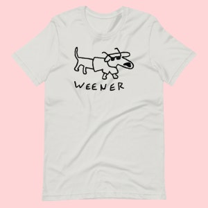 May include: White t-shirt featuring a black line drawing of a dachshund wearing sunglasses and the word "WEENER" underneath.