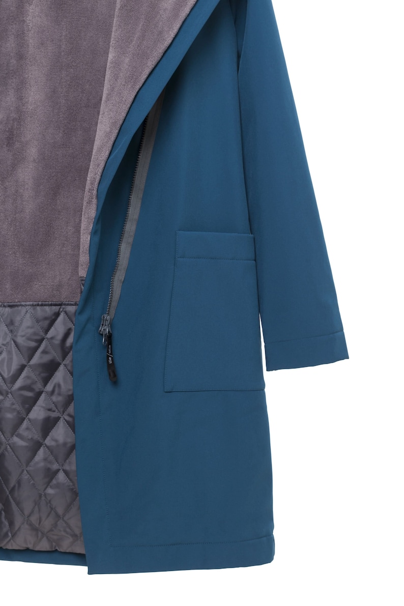 May include: A teal blue coat featuring a hood, a front zipper closure with a black pull tab, and a large patch pocket on the side. The interior is lined with a soft, dark gray fleece upper section and a quilted, diamond-patterned lower section.