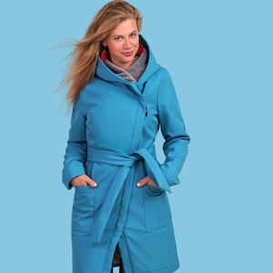 May include: A turquoise wrap coat with a hood and a matching belt. The coat has pockets and is made of a smooth material. The model is wearing a gray scarf and red earrings.