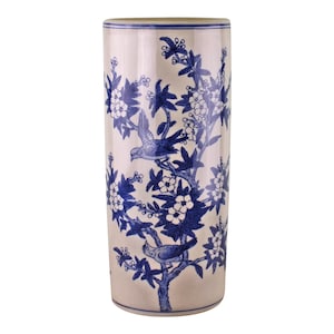 Pode incluir: Um suporte para guarda-chuvas de cerâmica branca com um design floral azul e branco com pássaros. O suporte tem uma forma cilíndrica e um acabamento liso e brilhante.