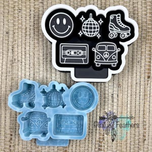May include: A black and white multi-shape cookie cutter featuring a smiley face, disco ball, roller skate, cassette tape, and van, paired with a light blue silicone mold of the same shapes, including the text Pine & Feathers in the corner.