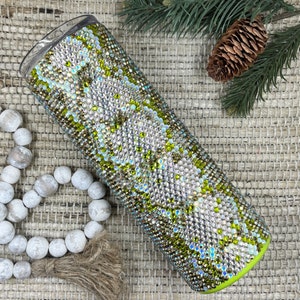 May include: A green and white tumbler covered in rhinestones. The tumbler has a clear lid and a green base.