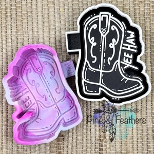 May include: A pink and purple gradient cowboy boot cookie cutter alongside a black and white cowboy boot cookie cutter. Both cutters feature a detailed outline of a boot with the text YEE HAW embossed on the side of the boot design.