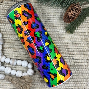 May include: A stainless steel tumbler with a rainbow-colored leopard print design. The print is made up of small circles in various colors, including red, orange, yellow, green, blue, purple, and black.