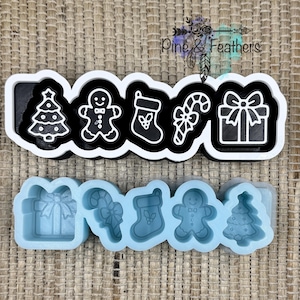 May include: A multi-piece cookie cutter set featuring a black and white frame with outlines of a Christmas tree, gingerbread person, stocking, candy cane, and gift box. Below is a light blue silicone mold with matching recessed shapes.