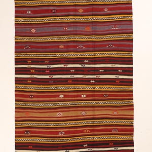 Peut inclure: Un tapis de couloir rectangulaire tissé à la main avec un motif à rayures. Le tapis présente des bandes alternées de rouge, marron, noir et jaune, avec de petits motifs en losange et géométriques. Le tapis mesure environ 91 cm de large.