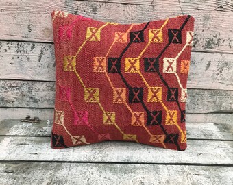 May include: A red, black, yellow, and white patterned throw pillow with a geometric design.