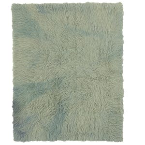 May include: A rectangular rug with a long, shaggy pile texture. The rug features a soft, muted sage green base color with subtle, cloud-like patches of faded blue throughout the surface, creating a soft, blended appearance across the fibers.