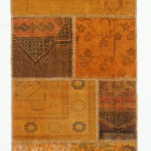 May include: A rectangular, patchwork rug with a variety of warm, earthy tones. The rug is composed of several rectangular and square patches in shades of brown, orange, and gold, with intricate patterns and textures.